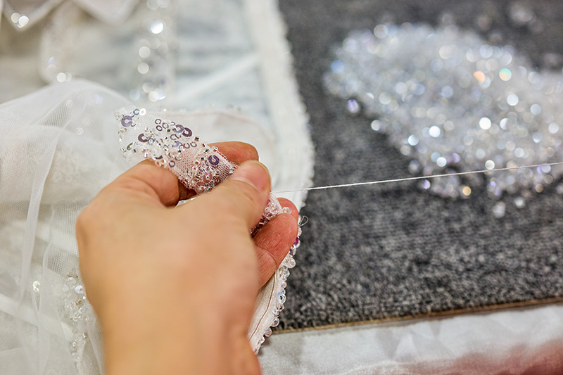 Couture-Kleideroberteil mit Nadelkissen während der Perlenarbeit